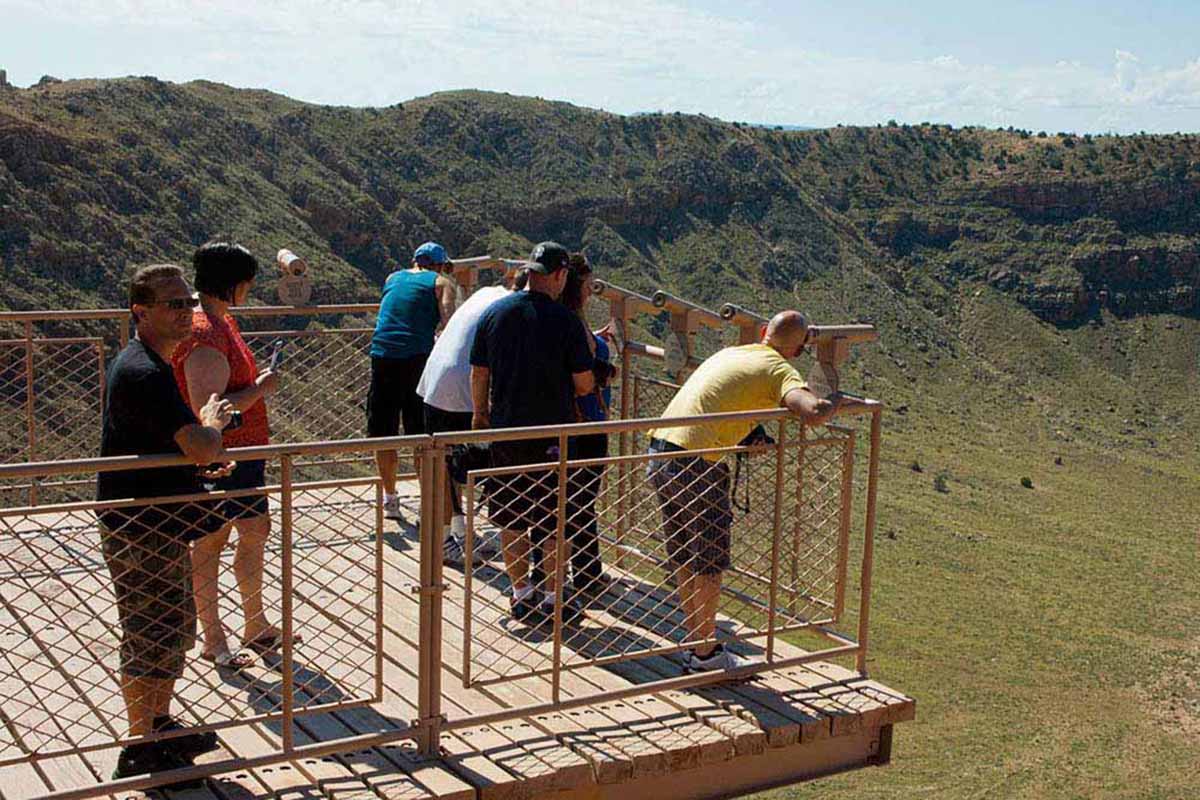 Meteor Crater — sightseers looking into a deep crater with telescopes.