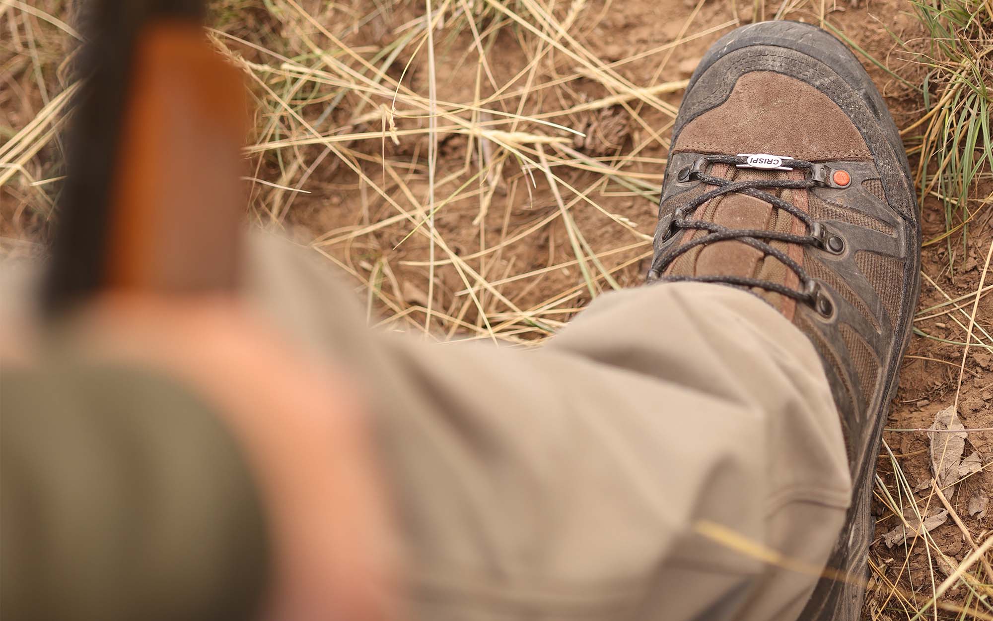 A hunter is holding gun and wearing upland hunting boots.