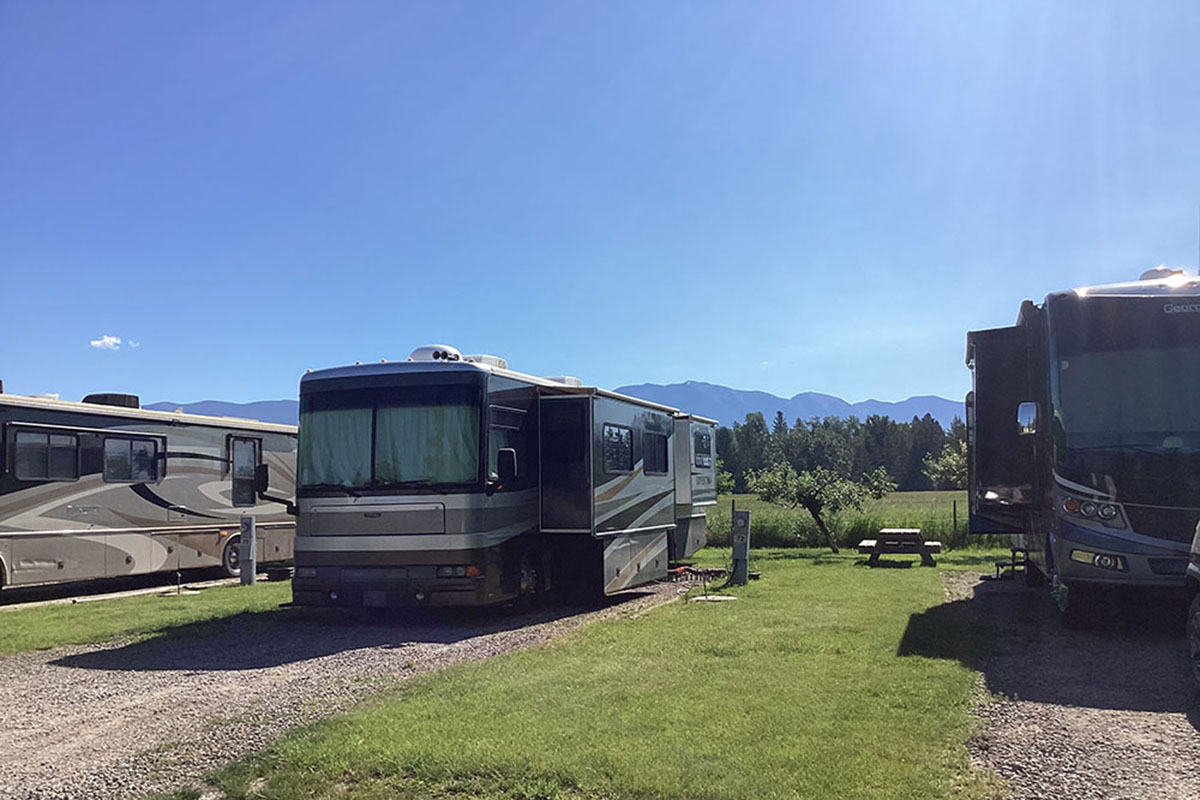 Motorhomes parked on gravel lots with mountain range in distance.