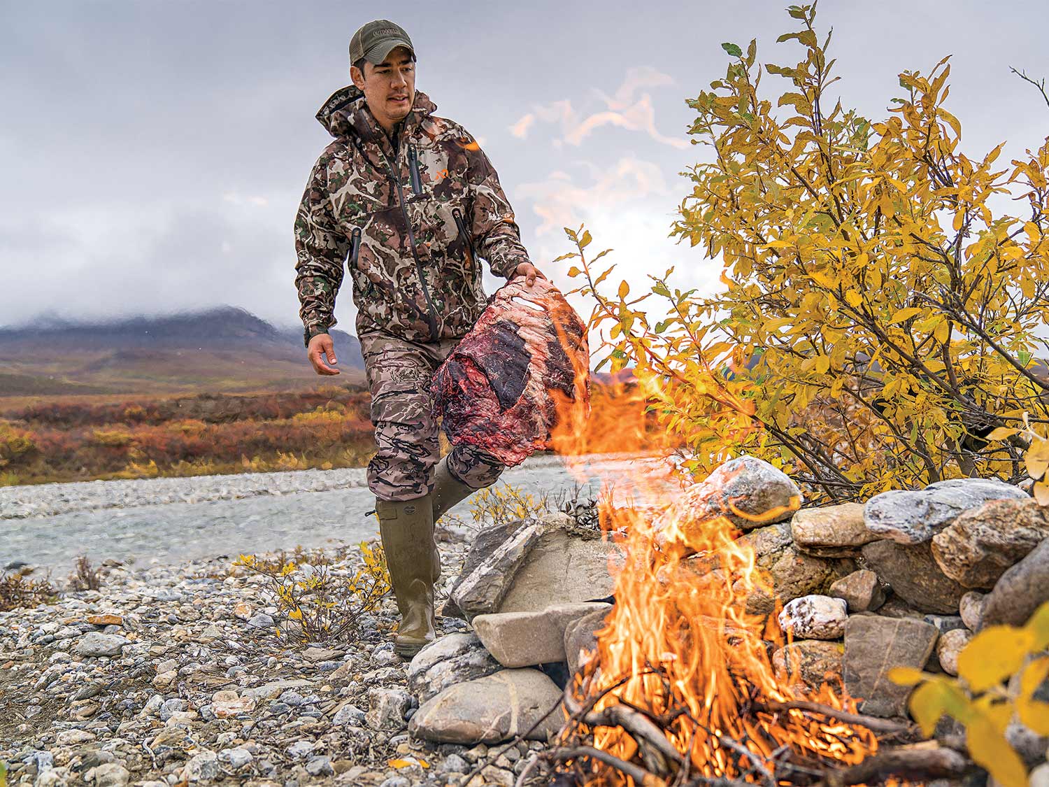 Alex Robinson carrying a piece of caribou meat to be smoked