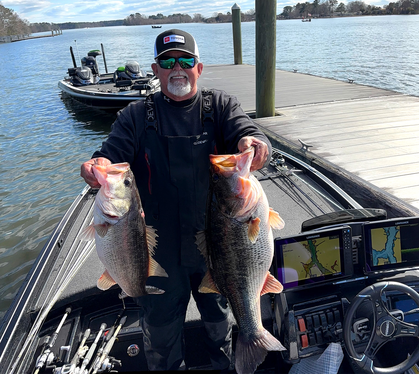 A tournament angler holds up two largemouth bass before weigh in.