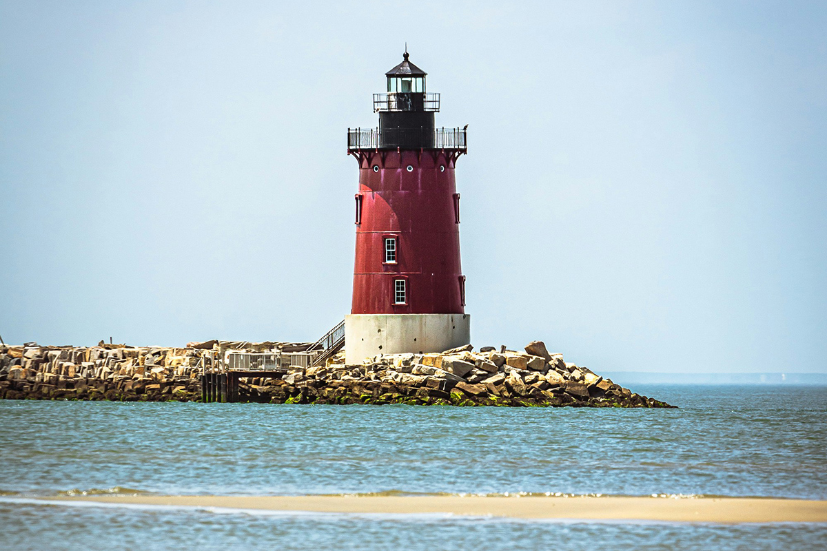 Lighthouse juts skyward at end of breakwater.