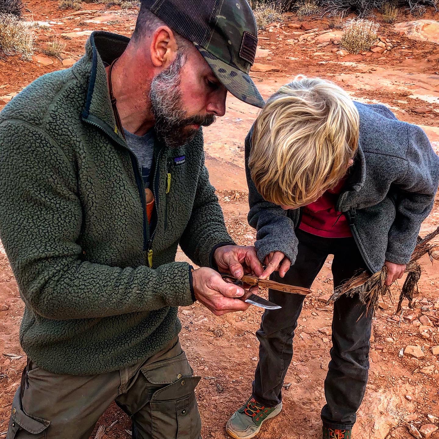 The author uses a survival knife to create a try stick. 