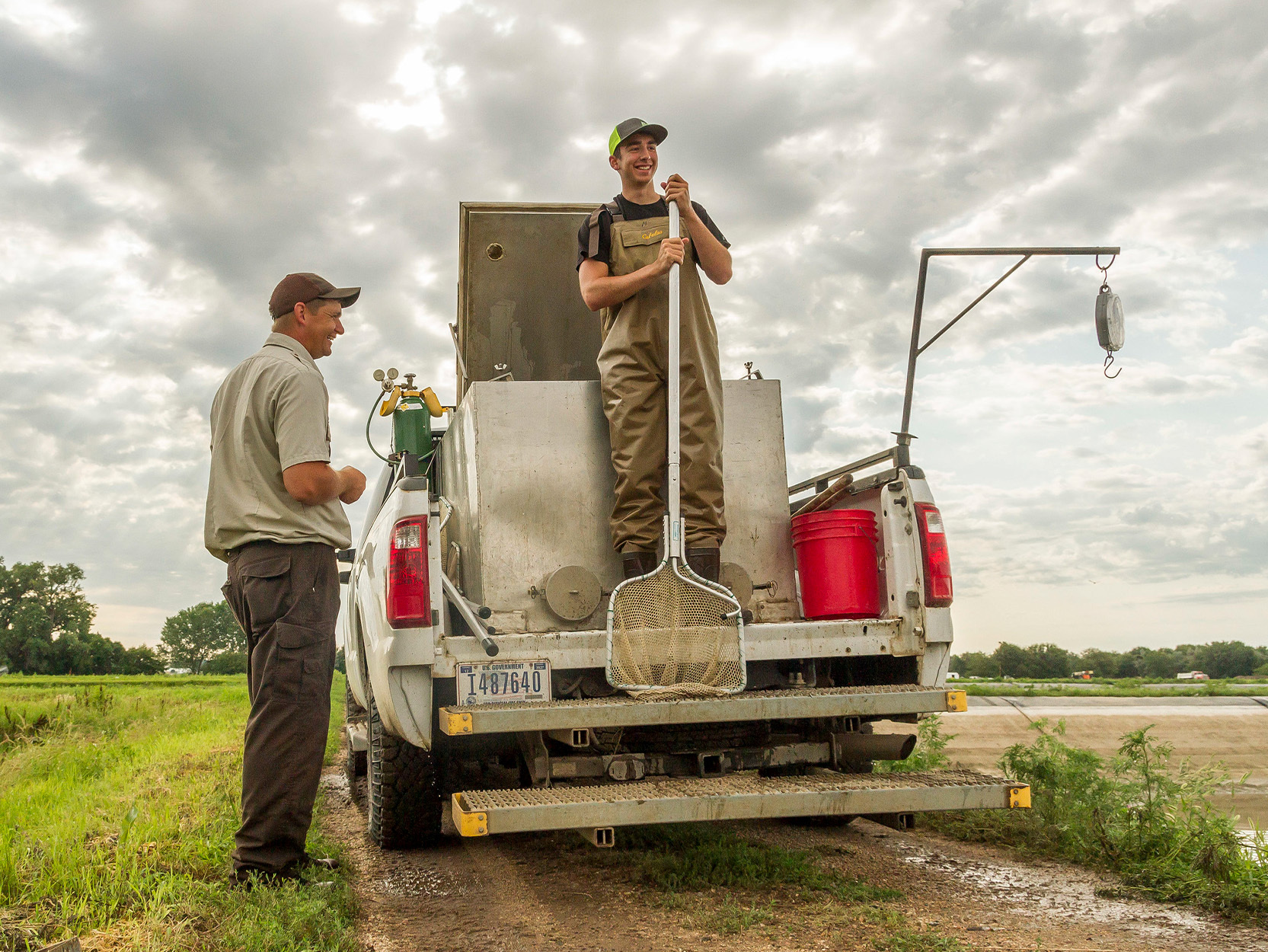 Two biologists stand on a gov't truck.