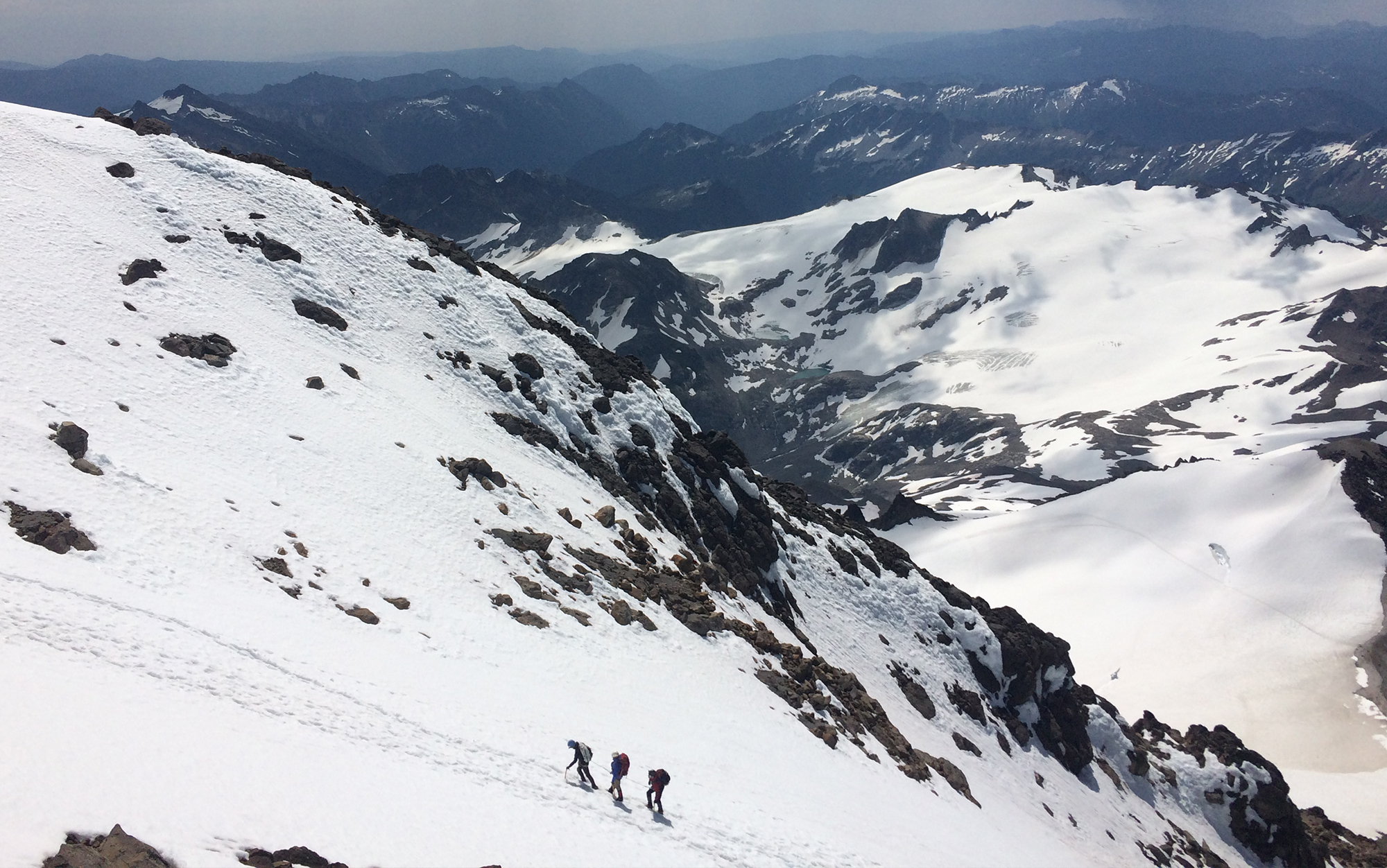 A rope team maneuvers up a snowfield. 