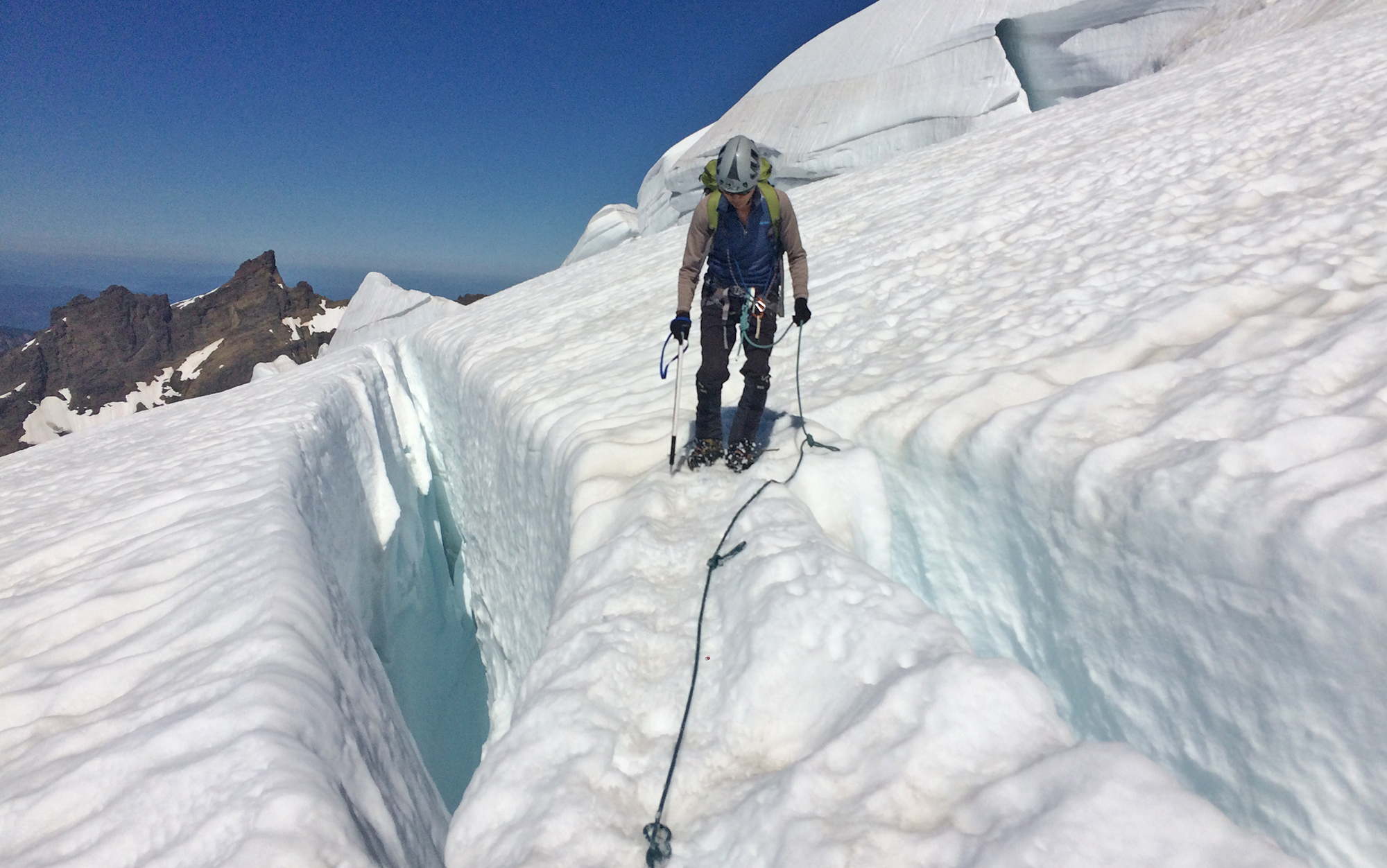 A climber walks between two crevasses.