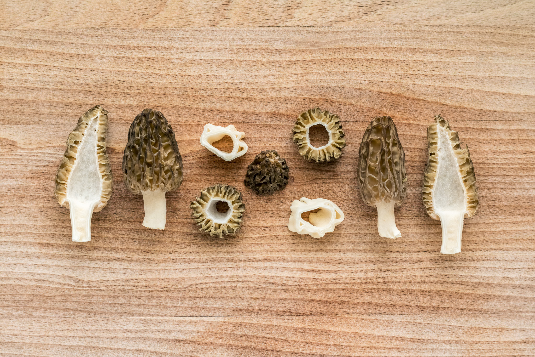 Slices of morel mushrooms on wooden cutting board