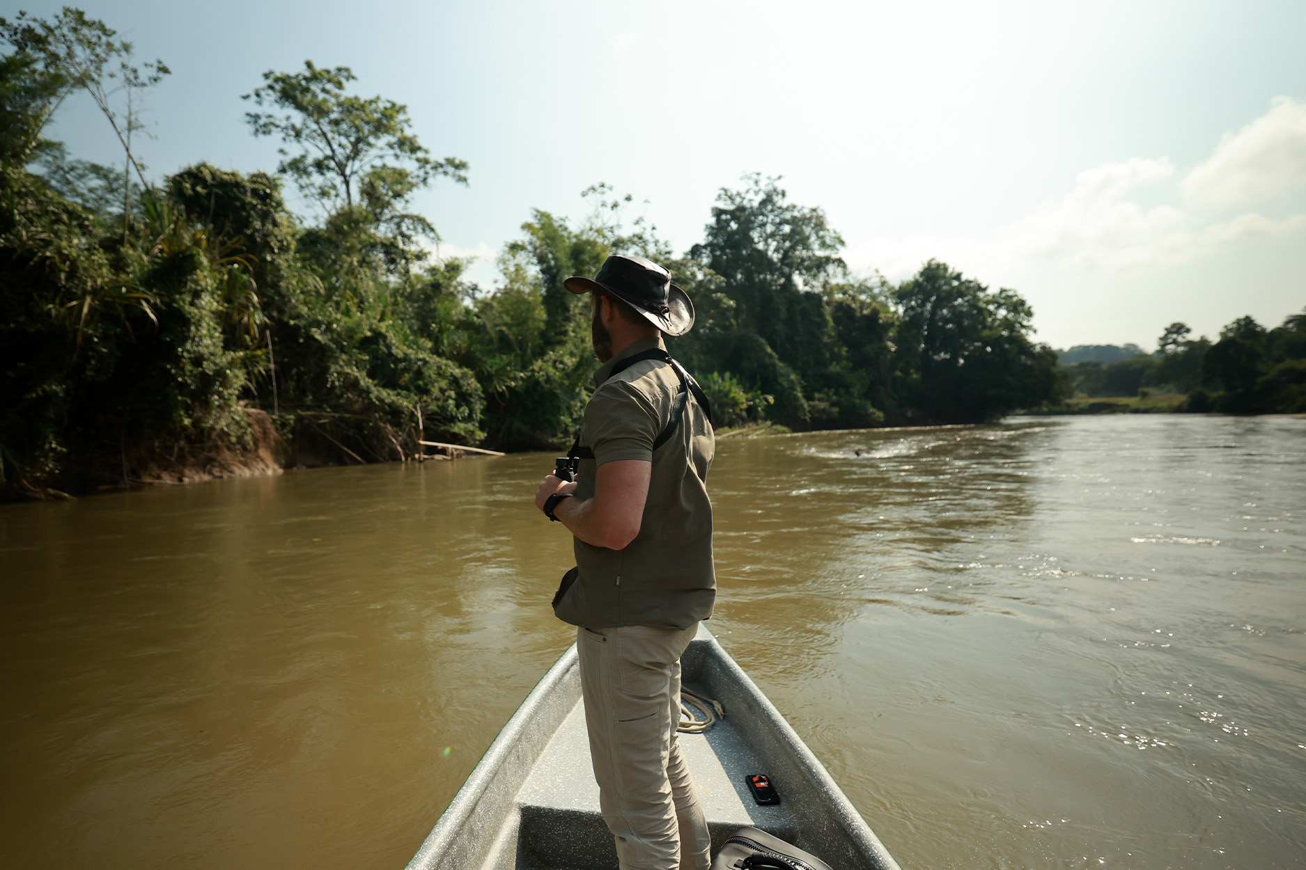 A biologist stands in the bow looking for hippos in a Colombian river.