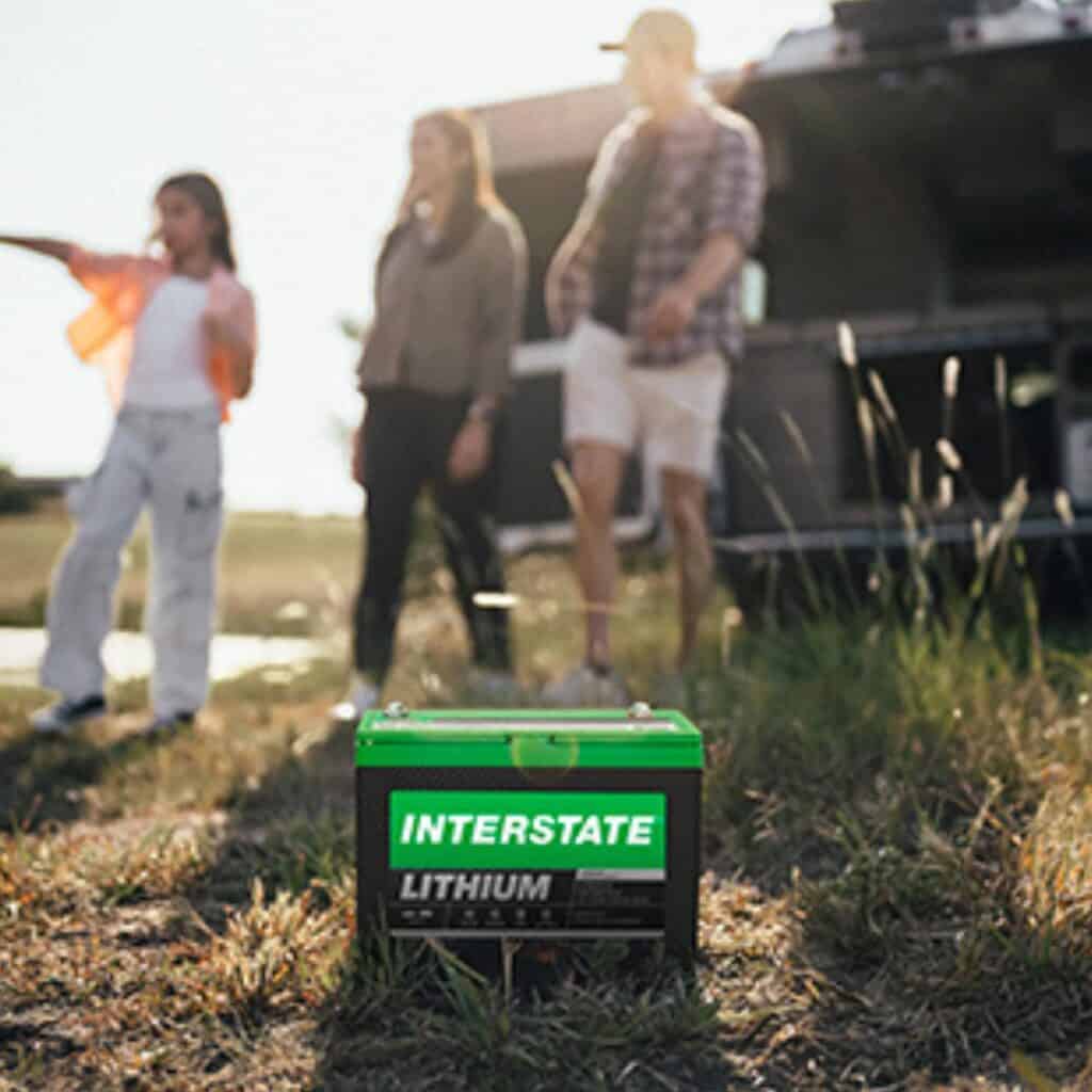 An RV lithium Battery sits on the grass in front of an RV