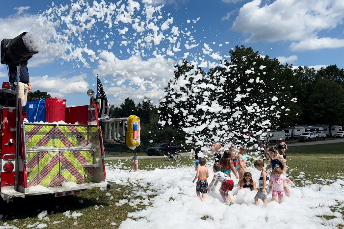 A firetruck sprays foam on kids at Roundup Lake. 