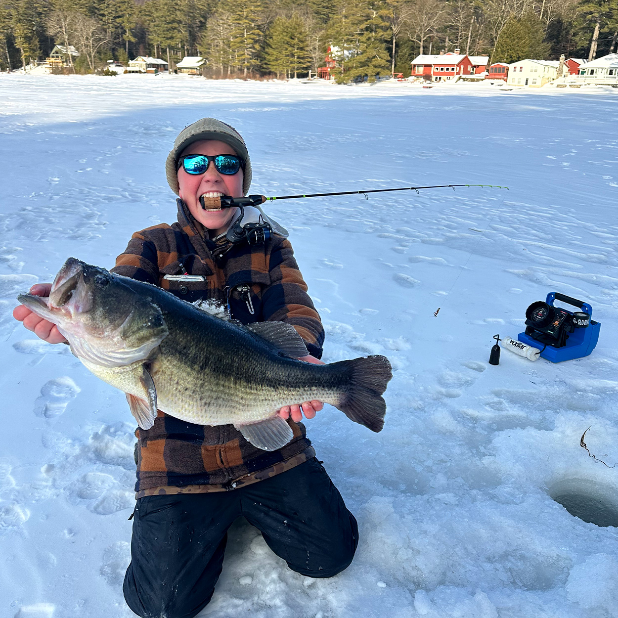 A teen angler in Massachussetts holds up a big bass caught through the ice.