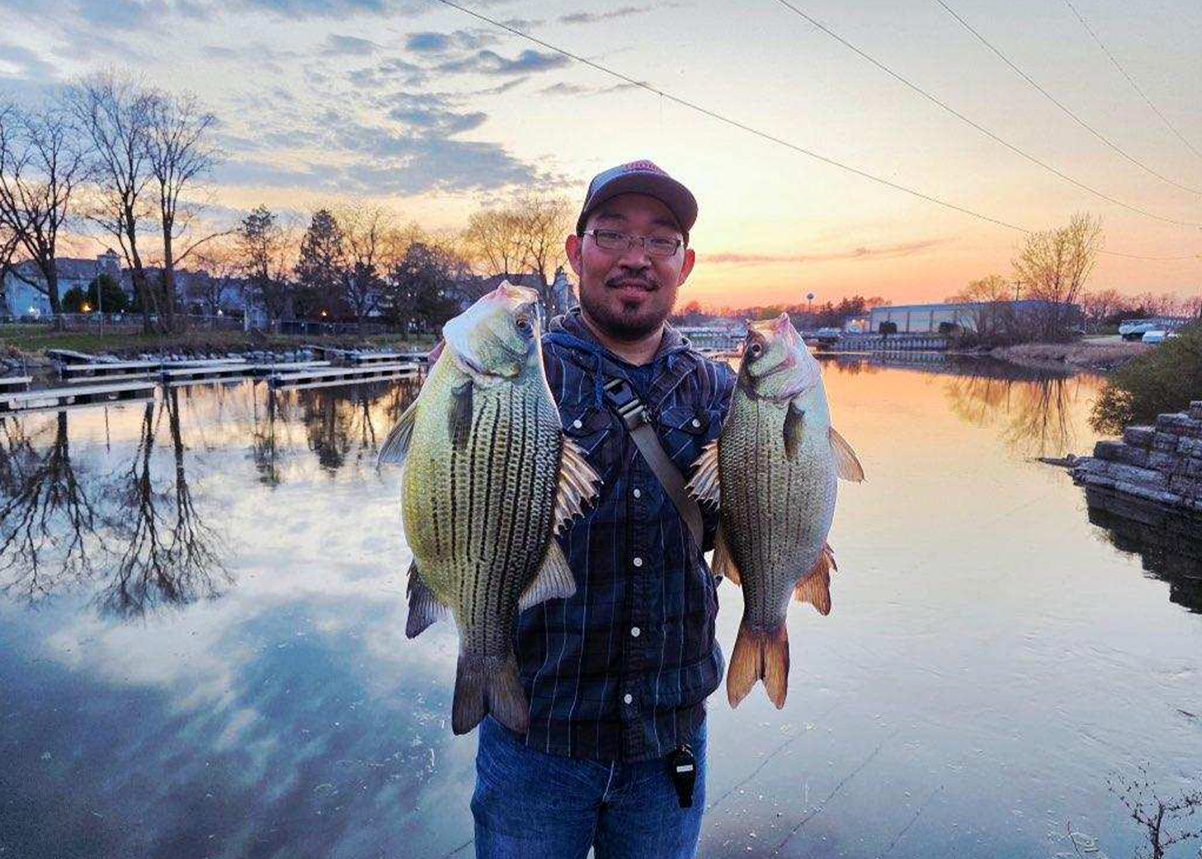 An angler holds up a chunky yellow bass alongside a keeper white bass.