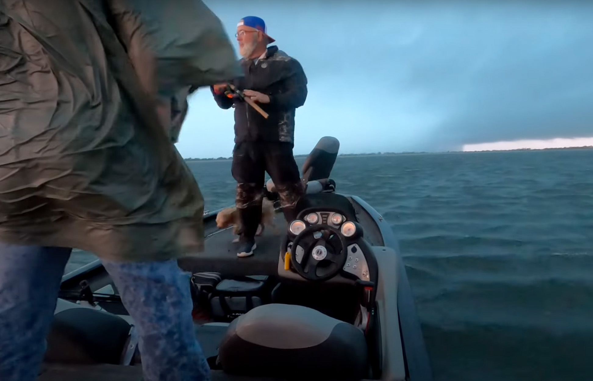 Two bass anglers on a boat with a storm in the distance.