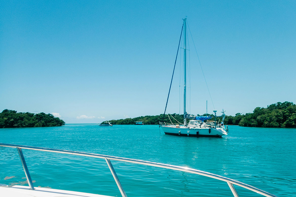 Sailboat moored over emerald-jeweled waters.