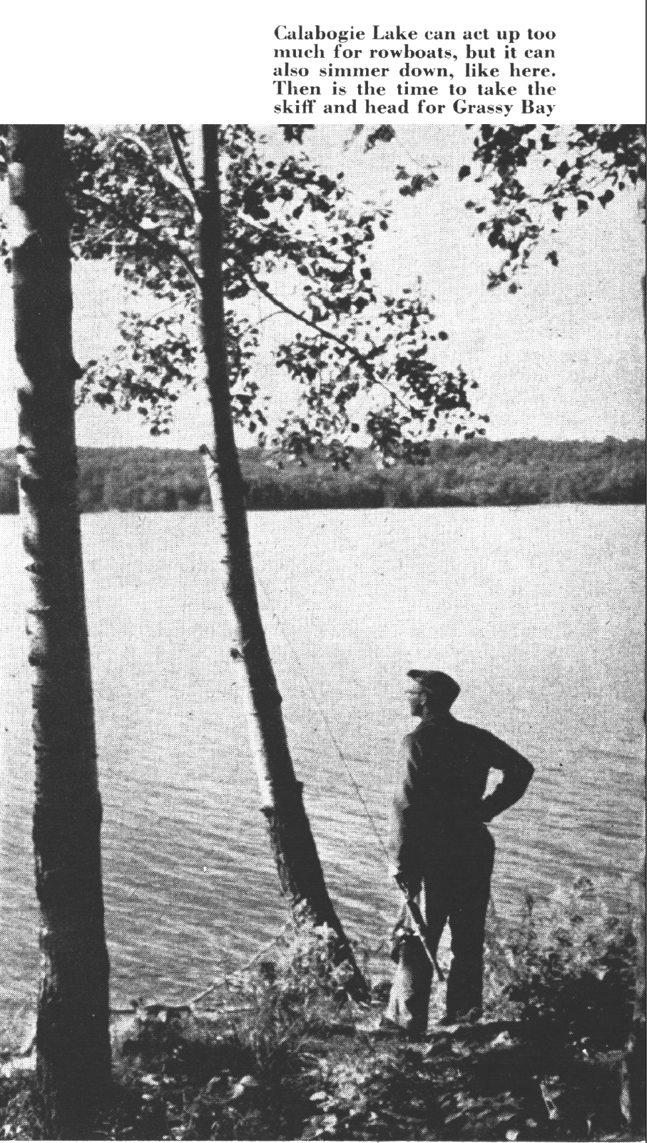 A fisherman stands on a lake edge in an old black and white photo