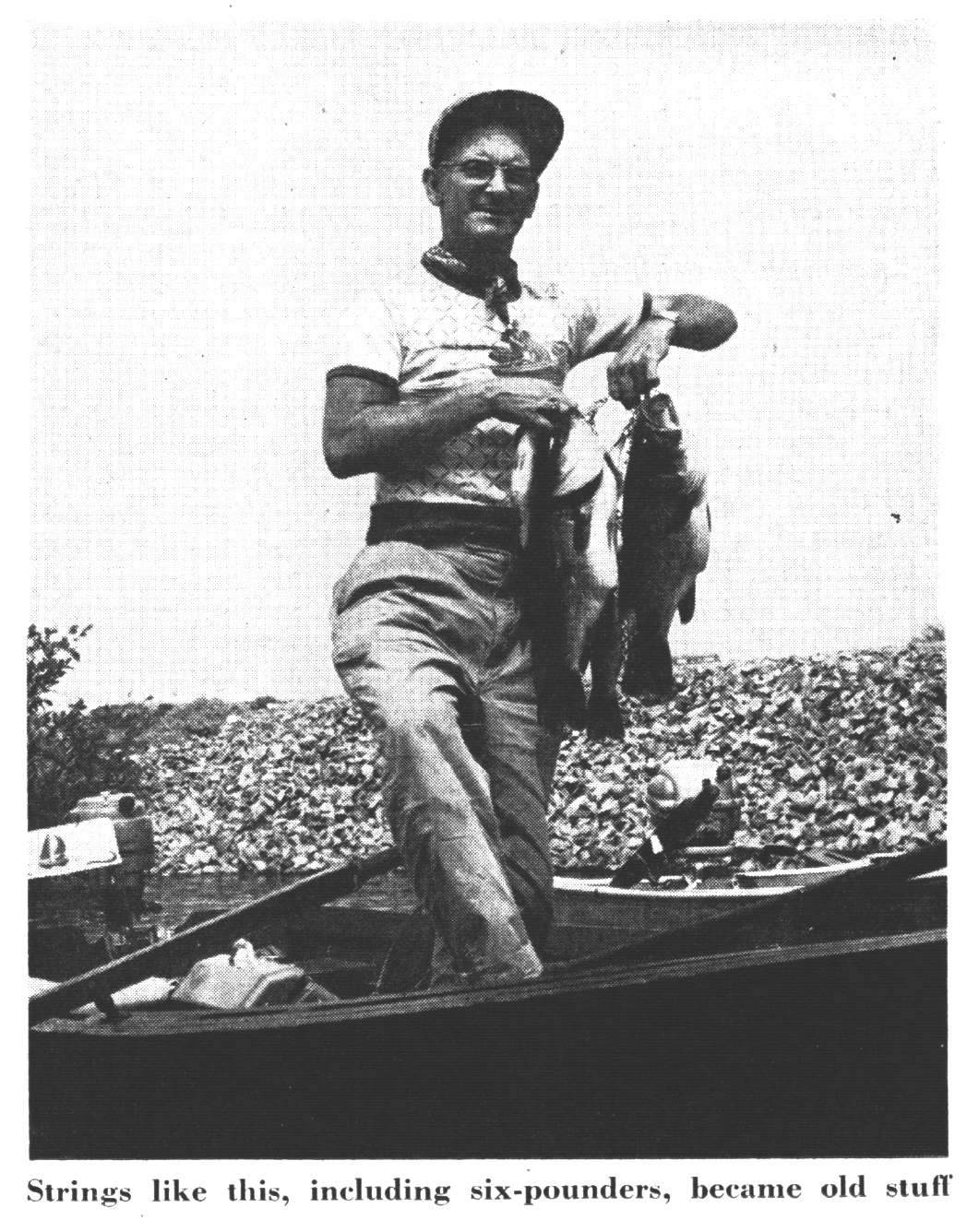 A fisherman holds up a stringer of bass in an old black and white photo