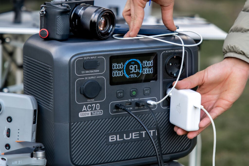 person plugging devices into a portable power station to use and stay cool off-grid