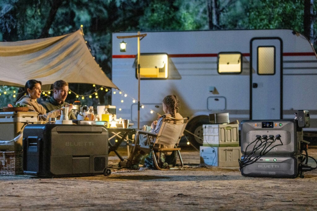 family sitting outside of RV with several devices plugged into a portable power station