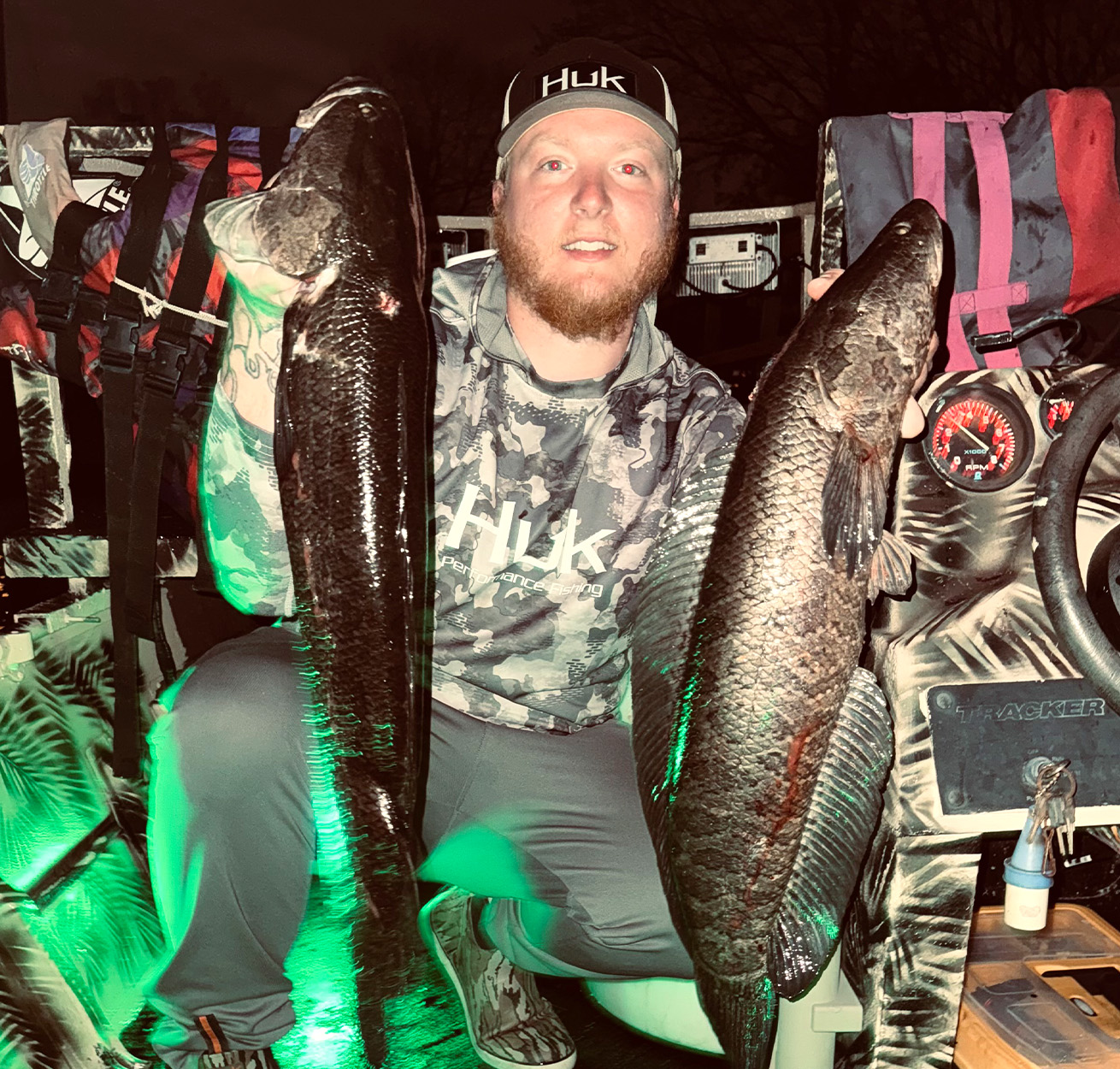 A Maryland bowfisherman holds up two snakheads.