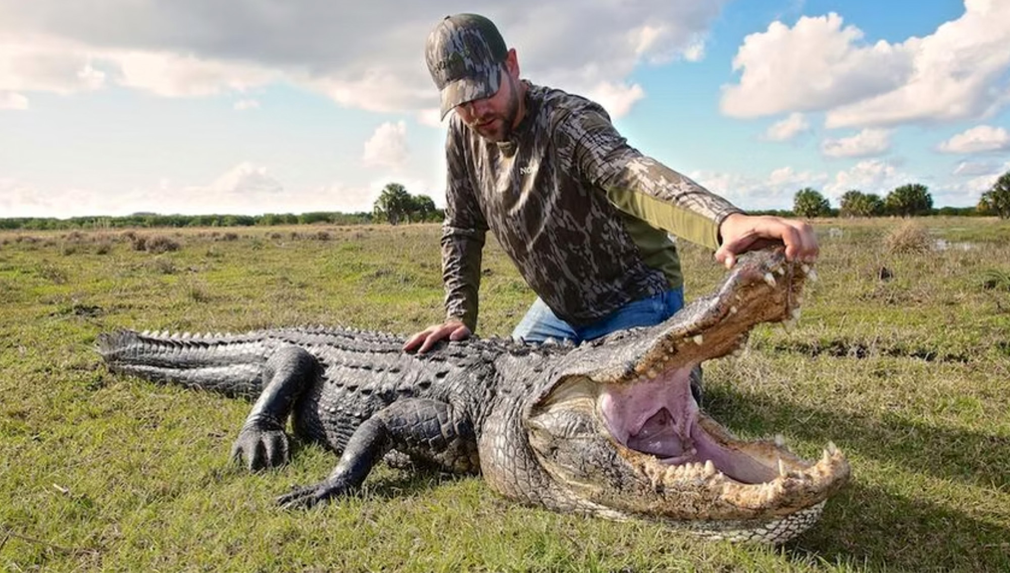 A hunter kneels beside a gator