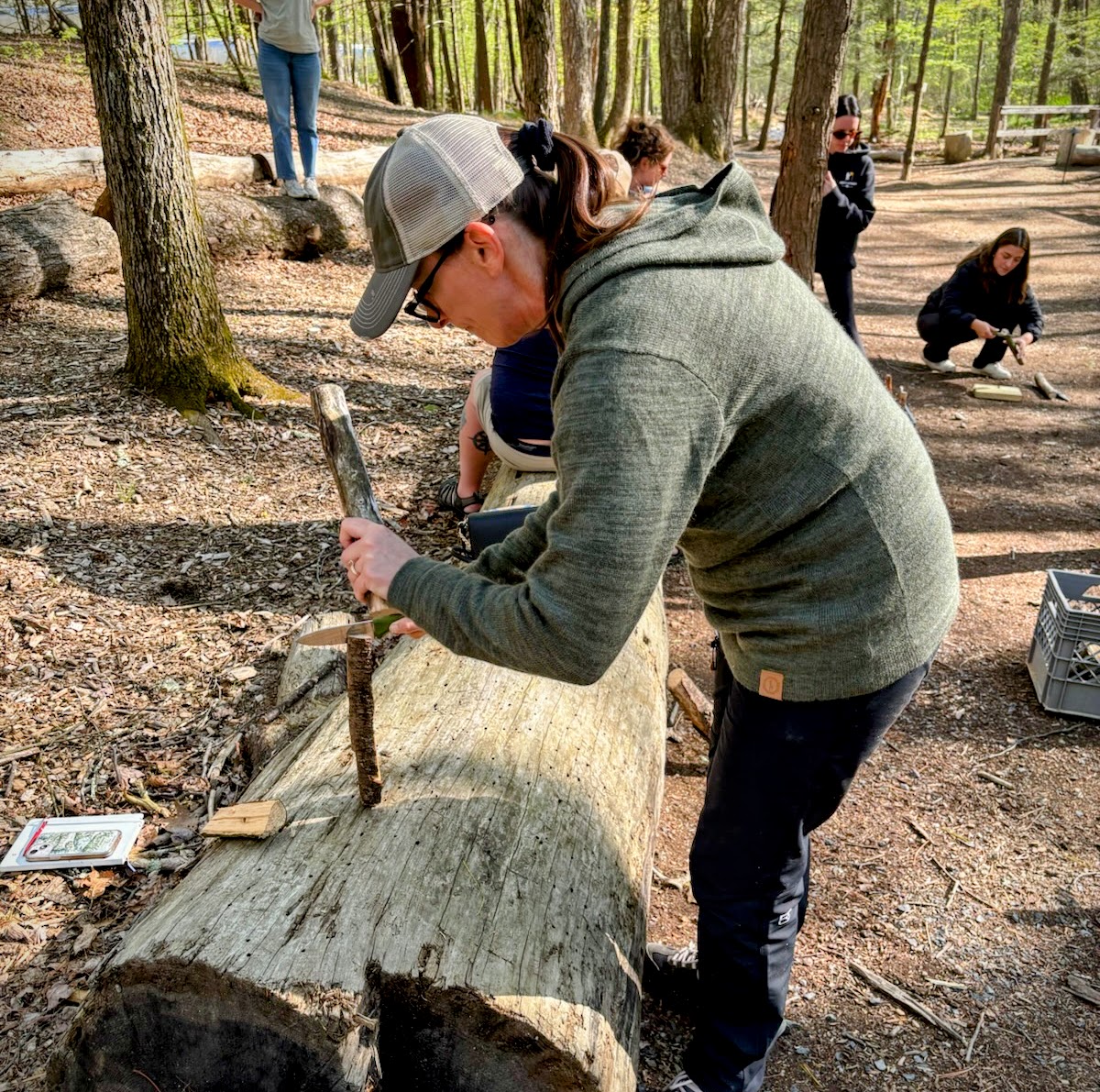A woman using a Victorinox Venture to baton kindling for a fire.