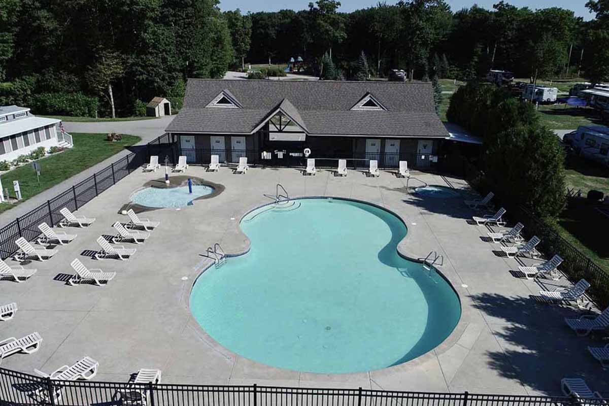 A pool forms an eight pattern and is surrounded by deck chairs near a clubhouse.