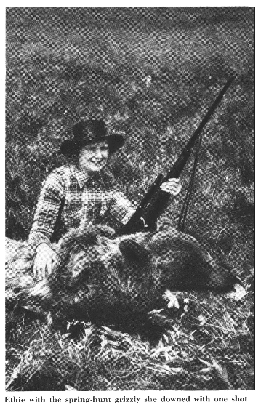 An old black and white photo of a woman beside a grizzly bear