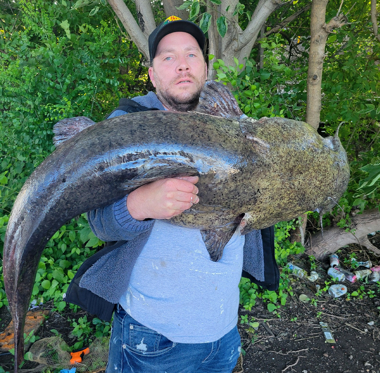 An angler holds up a flathead catfish caught in Philadelphia.