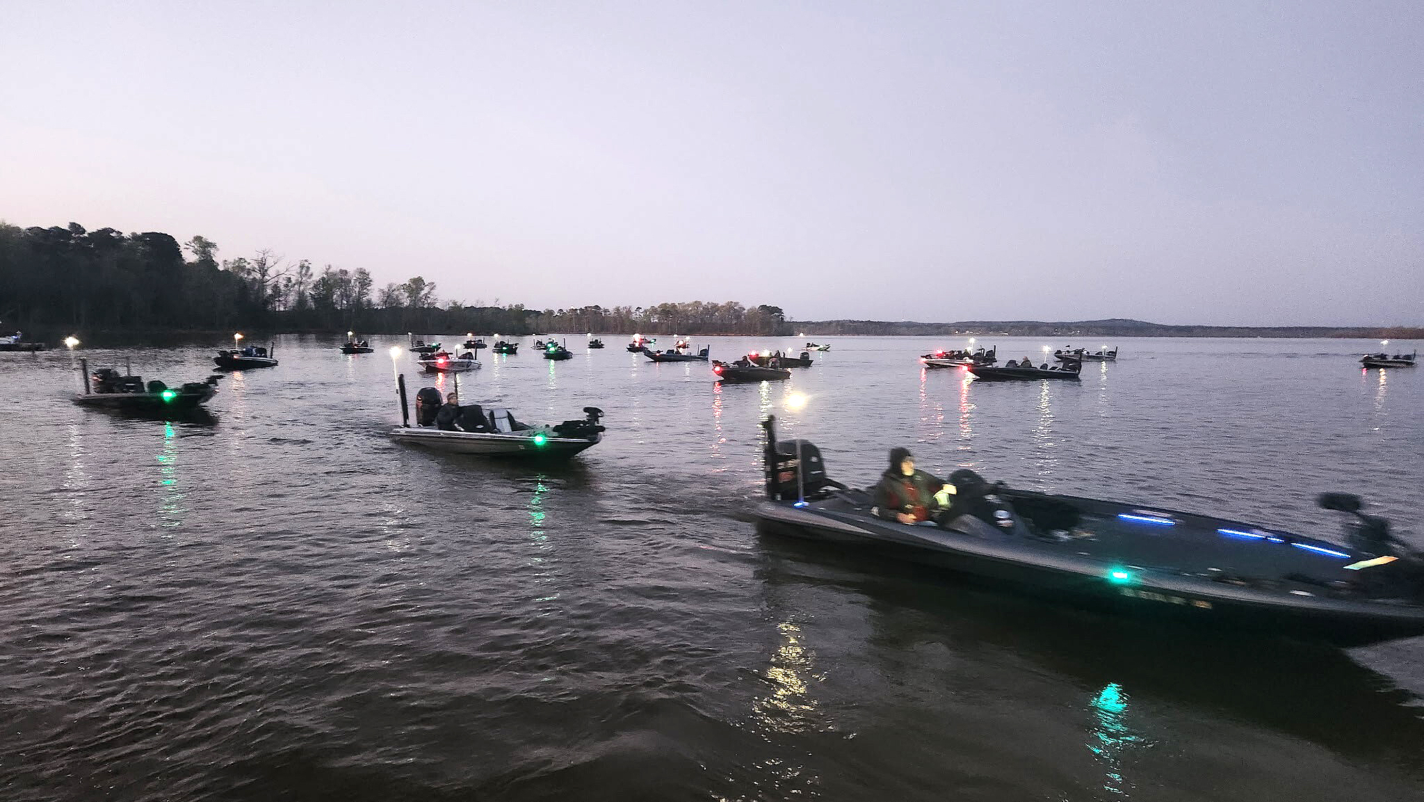 A group of bass boats on the water in the fog.